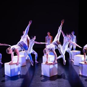 Dancers performing a symmetrical piece on stage.