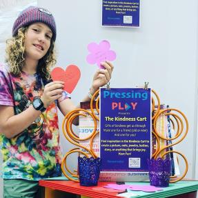 Child interacting with the "Kindness Cart" interactive art piece.