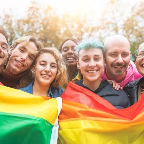 Diverse group of people holding up pride flags