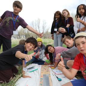 Students giving a thumbs up as they put their thumbprint on a sign for the Nest project