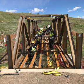 Construction workers laying boards on the deck of the South Bridge on North Sky Trail