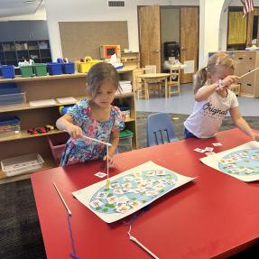 Two young students playing a fishing game on a school table.