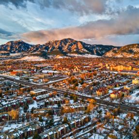 Drone view of University of Colorado, Boulder and the Flatirons at sunrise in the winter snow.