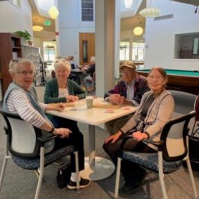 Four women sit around a table to play Mah Jongg at the West Age Well Center