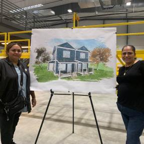 Future modular homeowners, Maribel Gonzalez and Dulce Rodriquez, standing with a rendering of the future modular homes.