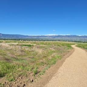 A wide gravel trail winding toward distant mountains