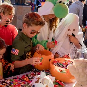 Kids dressed up in costume reaching for candy on a table in downtown Boulder