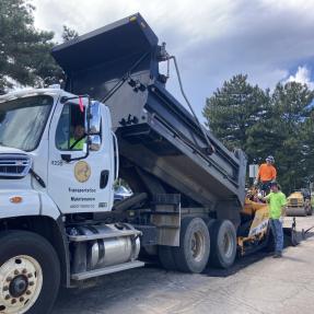 A City of Boulder dump truck unloading materials to repair a pothole.