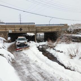 City truck with a plow blade on front clearing snow from a multi-use path.