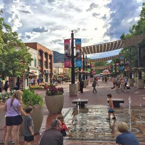 Pedestrians shopping, strolling and playing in the pop jet fountains on the Pearl Street Mall