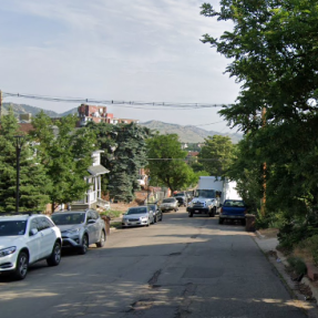 Before photo of Marine Drive without sidewalks. Cars are parked next to the left curb while the right curb is empty. 